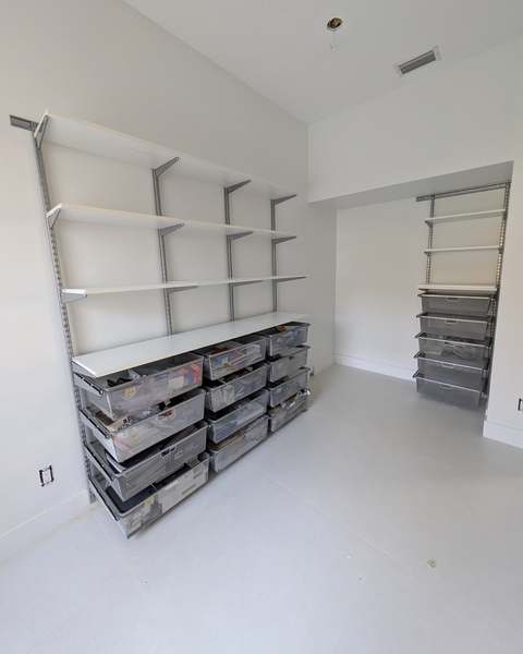 Wall-mounted closet shelving and drawer system installed in a walk-in closet