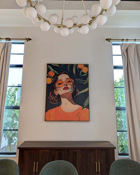 Large framed portrait hung centered between tall windows above a dining room sideboard