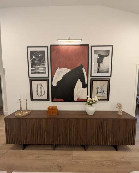 Four framed prints hung as an evenly spaced gallery wall above a walnut media console