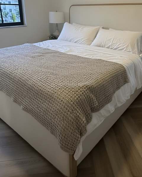 King bed frame assembled and made up in a bright primary bedroom