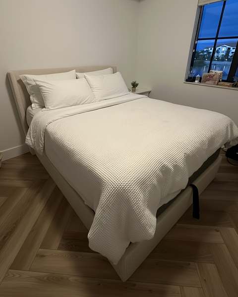 Platform queen bed assembled and dressed with white bedding