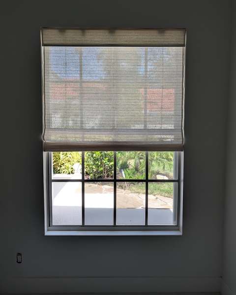 Roman shade installed inside a window frame on a charcoal wall