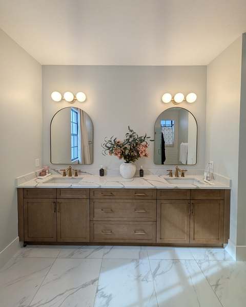Two arched mirrors hung evenly above a double bathroom vanity